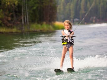 Wasserski Kinder: Junges Mädchen fährt auf einem See Wasserski.