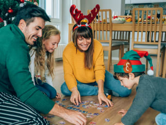 Kerstspelletjes voor kinderen: familie zit in de woonkamer op de grond en puzzelt.