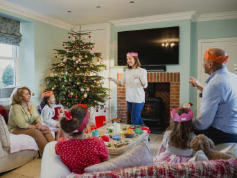 Kreative Weihnachtsspiele: Familie spielt im Wohnzimmer gemeinsam Scharade.