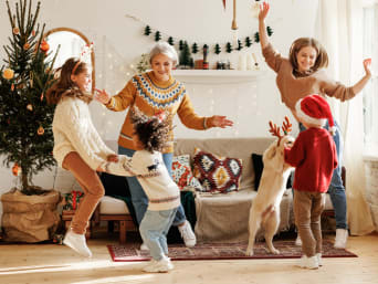Bewegungsspiele Weihnachten: Familie tanzt zur Weihnachtsmusik im Wohnzimmer.