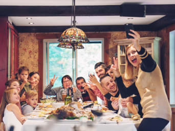 Kreative Familienfotos Weihnachten: Familie am Esstisch nimmt ein lustiges Selfie auf.