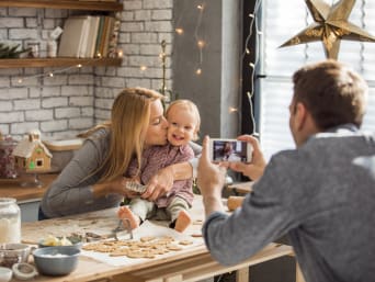 Weihnachtsshooting: Vater fotografiert Mutter und Kind beim Plätzchen backen.
