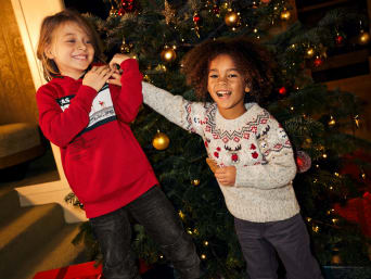 Weihnachtstraditionen: Zwei Kinder in Weihnachtspullovern.