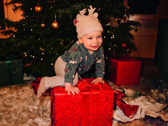 Pakjesavond: baby speelt onder de kerstboom.