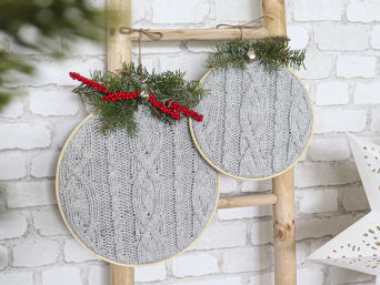 Upcycling Kerstmis knutsel idee: borduurraam bedekt met een oude gebreide sjaal met een vlechtpatroon.
