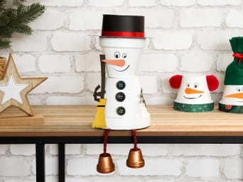 Manualidades navideñas fáciles para niños: muñeco de nieve con patas colgantes hecho de macetas de barro