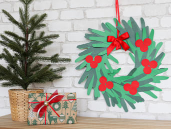 Adornos navideños para hacer con niños: una corona de Navidad con siluetas de manos de distintas tonalidades de verde.