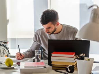 Berufliche Weiterbildung: Junger Mann lernt zuhause am Schreibtisch.