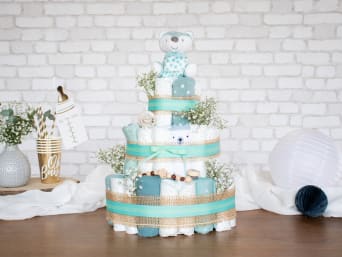 A DIY nappy cake with decorative materials.
