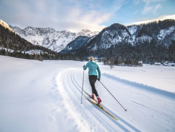 Die schönsten Langlaufgebiete in Österreich: Langläuferin fährt durch Schnee.