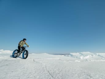 Nietypowe sporty zimowe – rowerzysta na fatbike’u jedzie po śniegu.