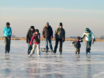 Patinage lac gelé Jura: une famille patine sur un étang glacé en France.
