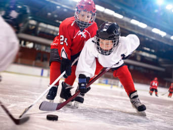 Leren ijshockeyen: twee kinderen oefenen ijshockey op een ijsbaan.