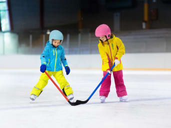 Eishockey spielen lernen: Zwei Kinder üben Eishockey in einer Eishalle.