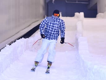 Skihal: Een skiër daalt een indoor skipiste af.