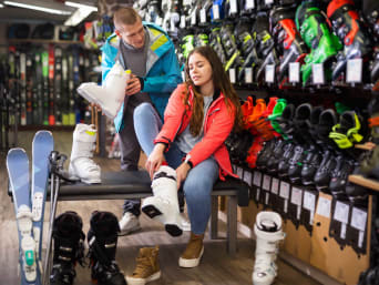  Uitrusting sneeuwhal: Een vrouw past skischoenen in een verhuurwinkel.
