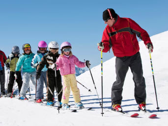 Apprendre à skier : un moniteur de ski enseigne et donne des conseils de ski à un groupe d’enfants.