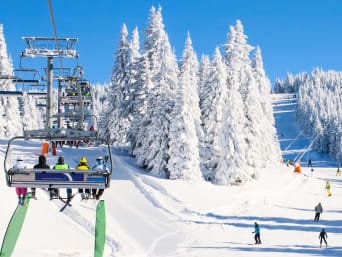 Skifahren Regeln: Familie fahren mit einem Sessellift den Berg hinauf.