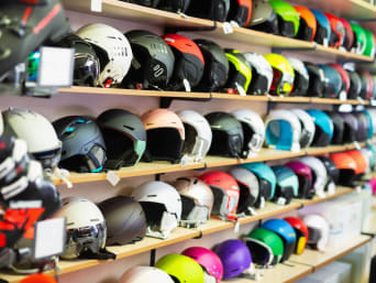 Equipo necesario para esquiar: cascos de esquí de varios colores expuestos en los estantes de una tienda.