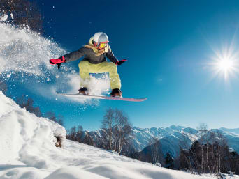 Jaka deska snowboardowa dla dziecka – snowboardzistka wykonuje skok na desce. 