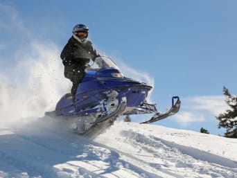 Deportes de invierno: un hombre hace una ruta con una moto de nieve.