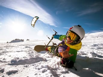 Trendsportart Snowkite: Snowboarder lässt sich von einem Zugdrachen ziehen.