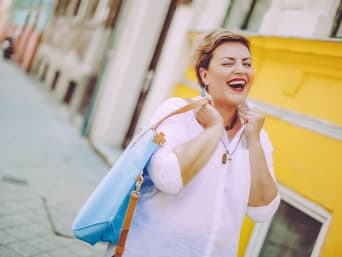 Smějící se žena s postavou obráceného trojúhelníku v bílé halence.