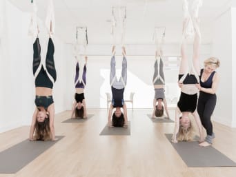 Aerial joga – grupa kobiet na zajęciach jogi na szarfach.