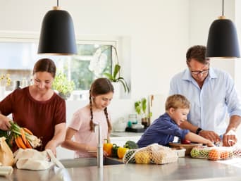 Réduire sa consommation de plastique : une famille déballe ses courses des sacs en filet et des sacs en tissu.