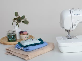 Workstation with a sewing machine and finished cloths along with other textiles for upcycling.