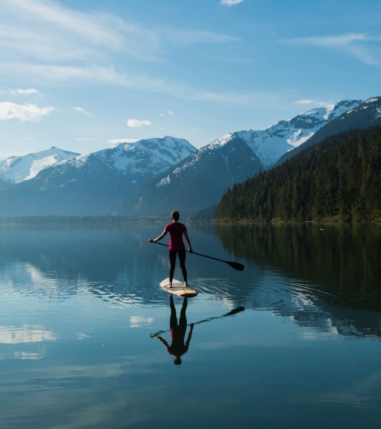 Paddle débutant : une femme fait du stand-up paddle sur un lac.