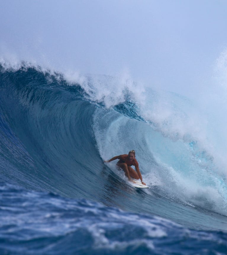 Surfing – młoda kobieta surfuje na fali.