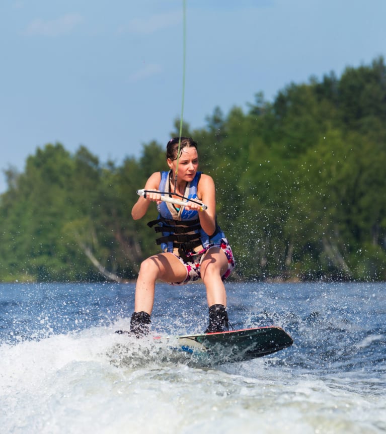 Wakeboard – Frau nutzt eine Wakeboard-Anlage auf einem See