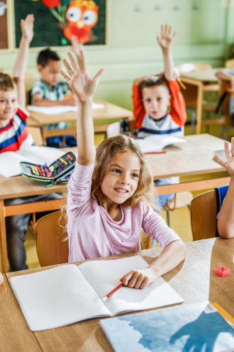 École primaire : des écoliers lèvent la main en classe.