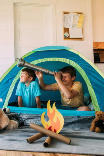 Gids ideeën voor vrijetijdsbesteding – Kinderen spelen met een tent in de woonkamer.