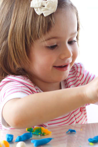 Qué regalar el Día del Niño: una niña pequeña juega con plastilina.