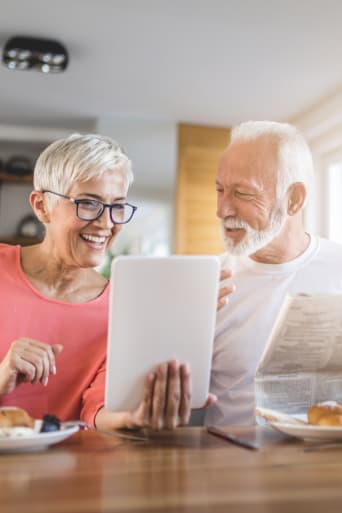 Bezpieczny Internet – para starszych ludzi czyta na tablecie podczas śniadania.
