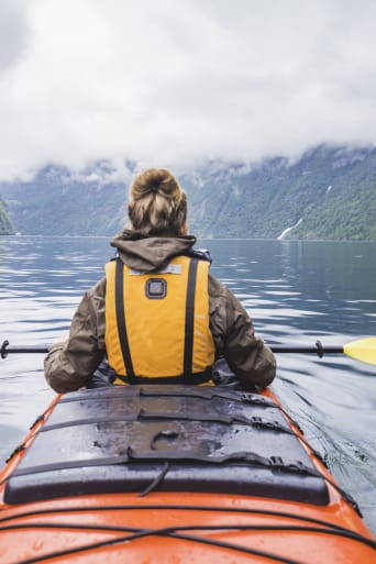Sports pour adultes : une femme fait du kayak sur un lac.