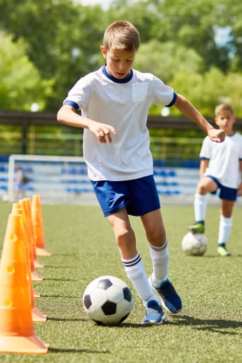 Calcio per bambini: un giovane ragazzo si allena assieme ai compagni di squadra in campo.