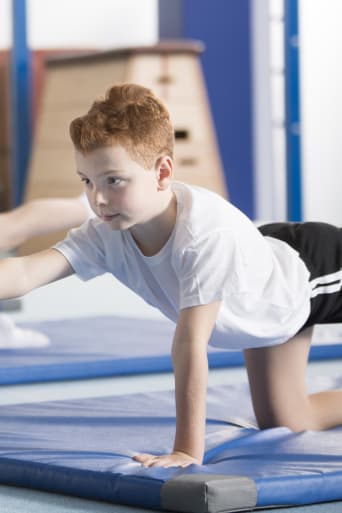 Gimnastyka sportowa dla dzieci – dzieci ćwiczące równowagę za pomocą ćwiczeń na macie.