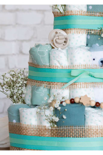 Gâteau de couches décoré avec des couleurs neutres et accompagné de différents cadeaux pour bébé.