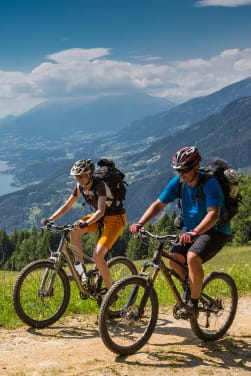 Fahrradtour planen: Zwei Radfahrer fahren oberhalb des Millstätter Sees in Österreich.