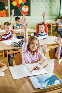 Basisschooltijd - leerlingen steken hun hand op om de vraag van de leraar te beantwoorden. 