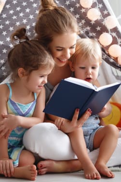 Lezen op jonge leeftijd aansporen: Moeder leest een boek voor aan haar twee kinderen.