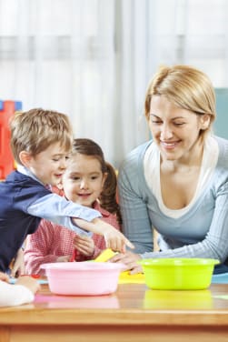 Leesspelletjes: Kinderen zitten aan tafel met een verzorger en leren spelenderwijs lezen