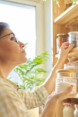 Estilo de vida sostenible: una mujer revisa los botes para almacenar alimentos de su cocina.