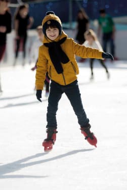 Eiskunstlauf für Kinder: Junge läuft auf einer Eisbahn Schlittschuh.