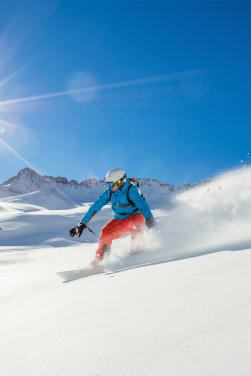 Wintersport: Wintersportler fährt auf einem Snowboard den Hang herunter.