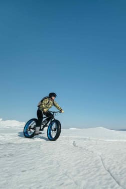 Trendsportarten Winter: Eine Frau fährt mit einem Fatbike durch den Schnee.