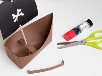 Bricolage anniversaire pirate : fixer la voile et le mât du bateau pirate.